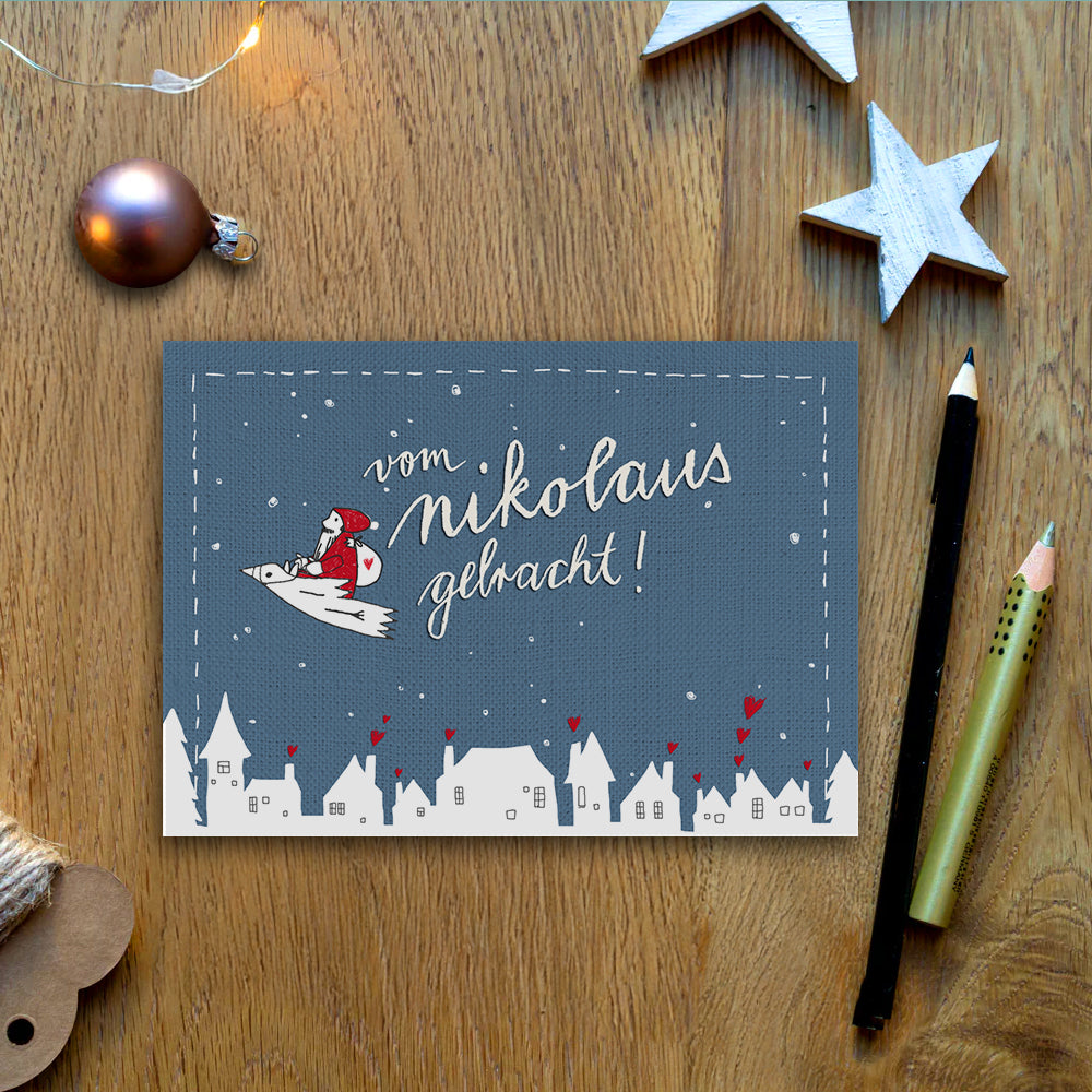 Weihnachtskarte - vom Nikolaus gebracht! | Witzige Weihnachtsgrußkarte mit fliegendem Nikolaus auf Vogel | Blau (Leinen Optik), Rot und Weiß